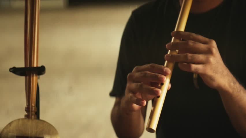Close-Up of Hands Playing a Bamboo Flute – Traditional Indonesian Wind Instrument Performance