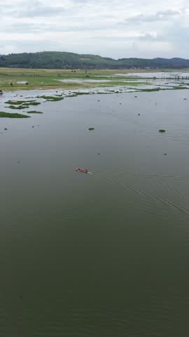 Drone Orbit Around Fisherman Boat on Rawa Pening Lake Beneath Majestic Mountains