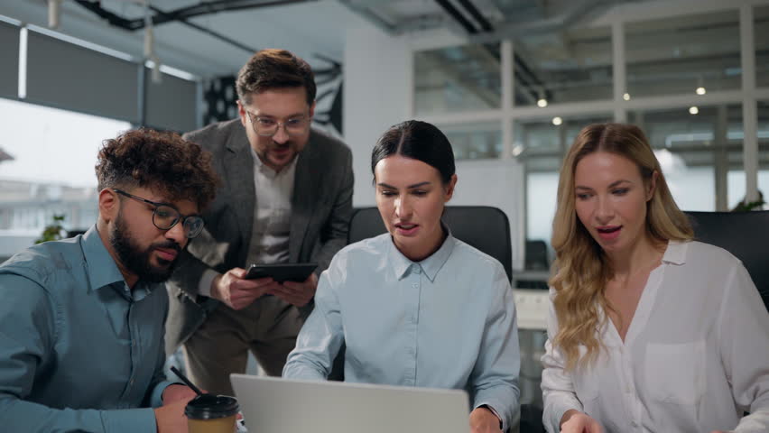 Four multiethnic business people working together with laptop talking winning job success giving high five celebrating multiracial businessmen and businesswomen colleagues win achieve team in office