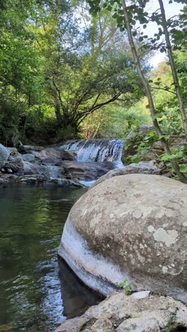 Small waterfall in nature with big rock in front 