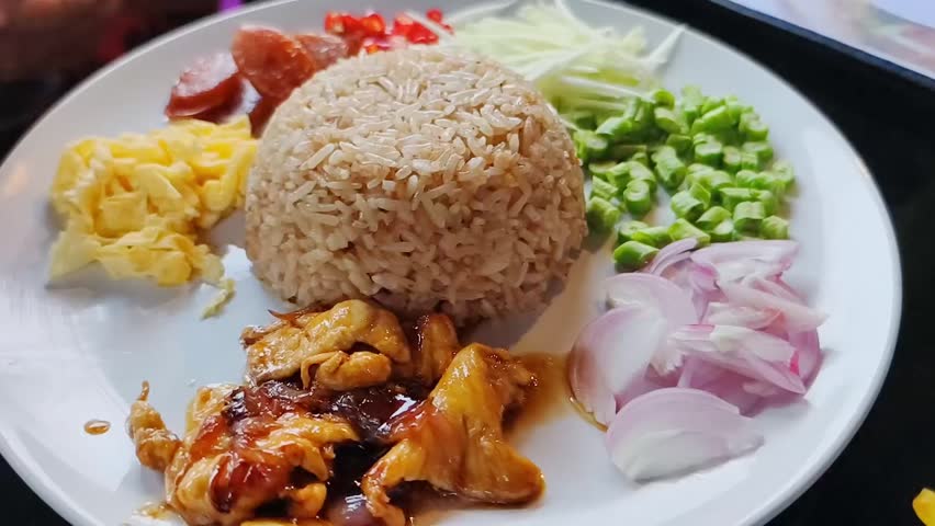A delicious and colorful platter of rice with various toppings, including chicken, egg, and fresh vegetables