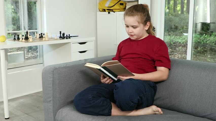 Child read book in cozy room. Kid reading big book with smile. Clever student read book. Cute child studying and reading book at home. Boy learning from books.