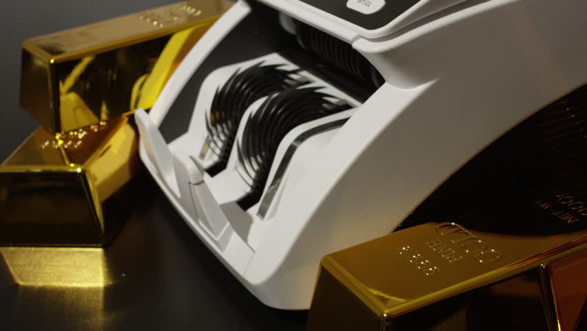 Money counting machine processing hundred dollar bills. Gold bars and US dollars. Money counting action. Banking operation with money and gold. Counting machine for money theme.