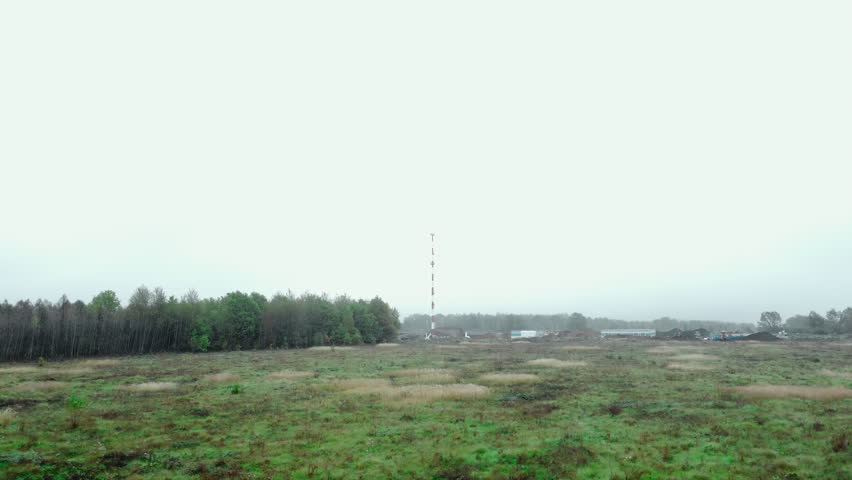 Wide rural meadow with distant tree line under cloudy sky
