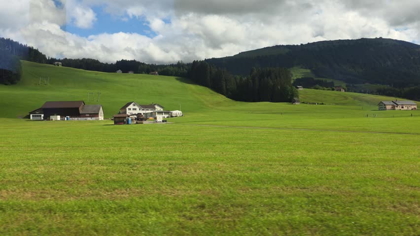 Beautiful green landscape in Switzerland featuring rolling hills, lush meadows, and majestic mountain scenery under a clear blue sky. Perfect for travel, nature, and outdoor-themed projects.