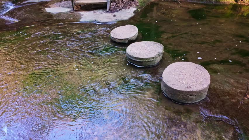 Stepping stones cross a creek with a cascading waterfall along a scenic hiking trail in Matthiessen State Park Illinois