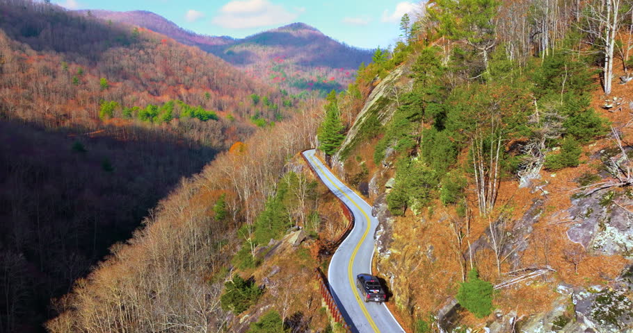Scenic journey through Highlands Road in North Carolina. Rocky mountainsides and fall forest canopy create a stunning autumn drive.