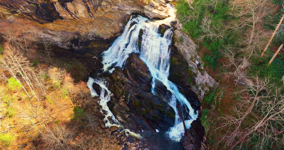 Majestic waterfall in Appalachian mountains, USA. Cullasaja Falls with rushing water tumbling over rocks during fall foliage season. A highlight of North Carolina scenic byways