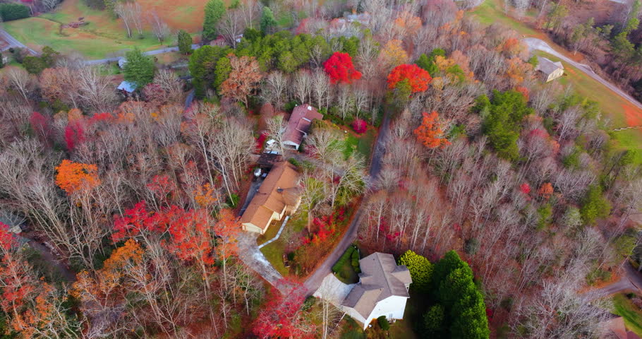 Small countryside houses scattered across the colorful North Carolina landscape. Appalachian mountain slopes covered with vibrant fall foliage