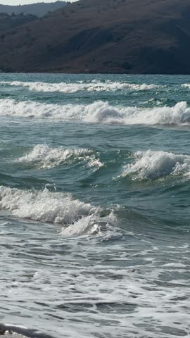 Waves roll onto the shoreline at Kavros Beach in Crete, Greece. Crystal-clear Mediterranean water, sparkling surf and a scenic coastal backdrop create a peaceful summer seaside atmosphere.