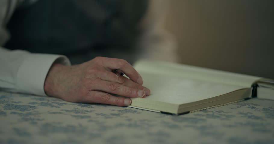 Close up of a hand in a white shirt sleeve pointing at a paper map on a table
