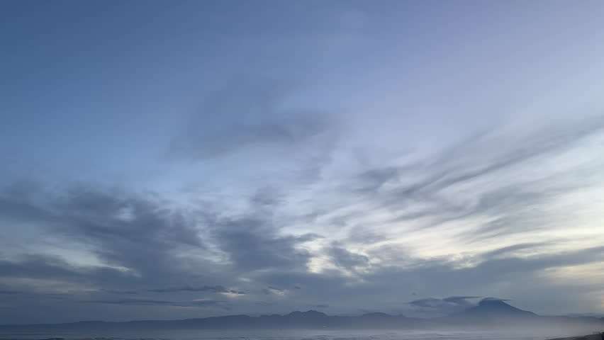 Flowing Clouds Sweeping Across the Sky Above a Coastal Landscape with Mount Fuji