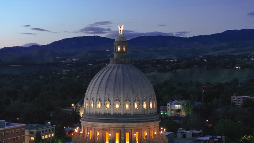 rotating shot at dusk of the dome on the idaho capital. Warm light outlines its architectural beauty. Mountain silhouettes stand in the background.