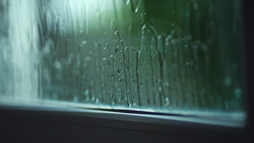 Close up of heavy rain droplets streaming down window glass pane, wet windowpane during monsoon summer storm, abstract natural rain background, cozy stay home and rainy season climate concept