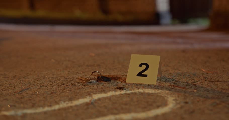 A close up view of a crime scene evidence marker with the number two next to lost keys on the ground at a scene.