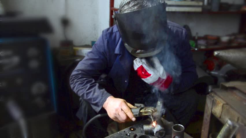 Industrial worker welding, Welder uses torch to make sparks during manufacture