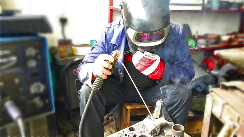 Industrial worker welding, Welder uses torch to make sparks during manufacture