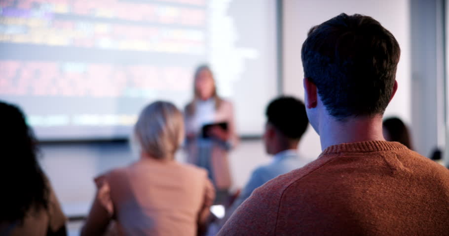 Students, lecture and raised hand in classroom at college, talk and coding course for education. Person, IT professor and questions with tech, learning and screen for programming in university hall