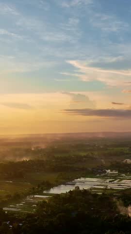 Golden sunset illuminating a sprawling countryside with reflective wetlands and distant horizons.