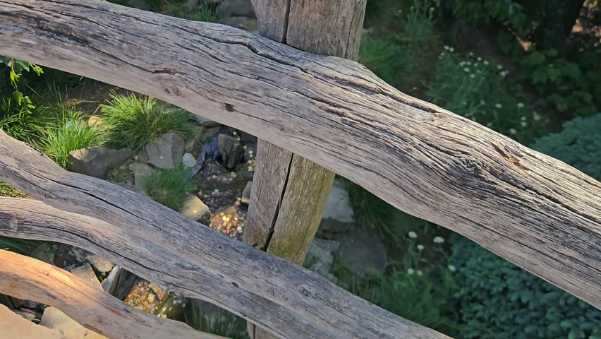 A detailed view of a rustic wooden structure adjacent to a shallow stream bed containing numerous coins and natural stones