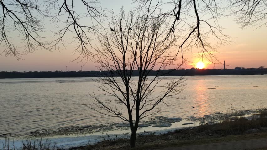 Spring sunset over a river with melting ice reflecting warm golden evening light.