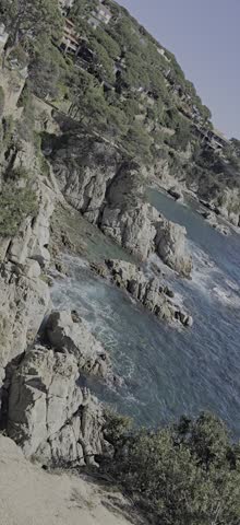 Short video showcasing the stunning rocky coastline of Lloret de Mar on Costa Brava, Spain. Crystal-clear turquoise waters of the Mediterranean Sea, dramatic cliffs, lush green vegetation, and a bright blue sky create a peaceful and scenic travel destination. Ideal for tourism, vacation, nature, and coastal landscape concepts.