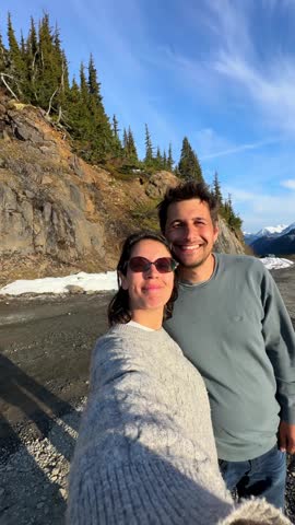 Happy couple taking a selfie video at Salmon Glacier in British Columbia, Canada