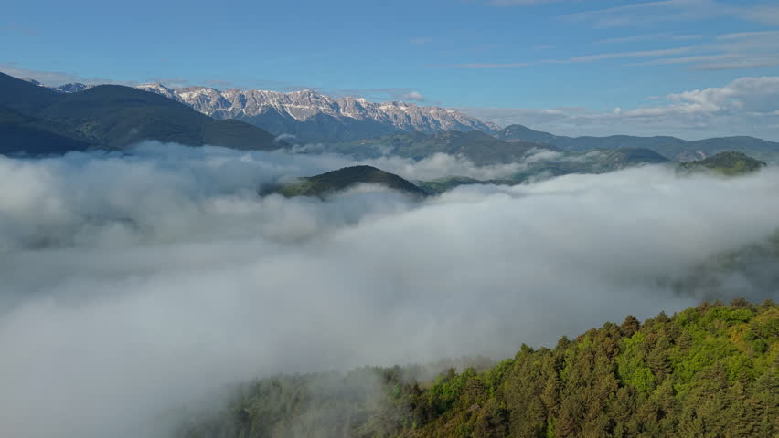 Snow capped Pyrenees mountains rising above sea of clouds in Catalonia