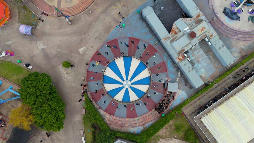 Overhead view of spinning amusement park ride with people seated in a circular pattern