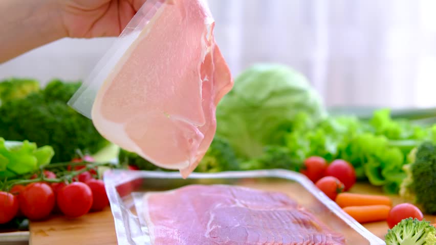 female hand holding prosciutto on kitchen background delicious thin slice