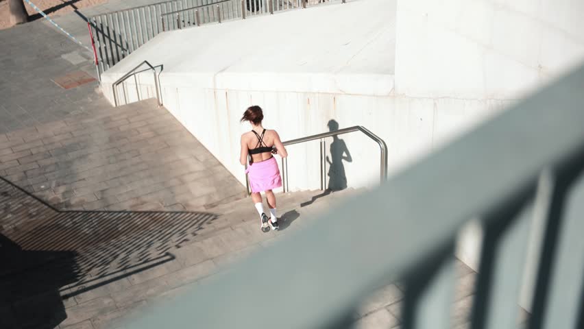 Young female runner stretching and exercising outdoors near a modern waterfront building.