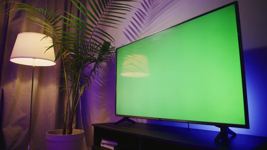 A sleek modern LCD TV displays a vibrant green screen in a cozy living room. Ideal for presentations, advertising, or creative projects. Perfect ambiance with stylish decor and lighting