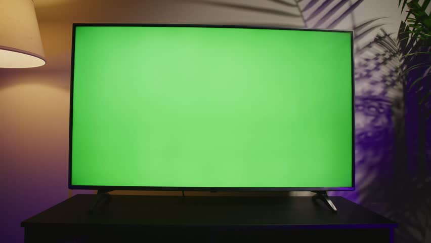 A modern living room features a large smart TV displaying a vibrant green screen. The perfect backdrop for creative works, this space invites comfort and relaxation