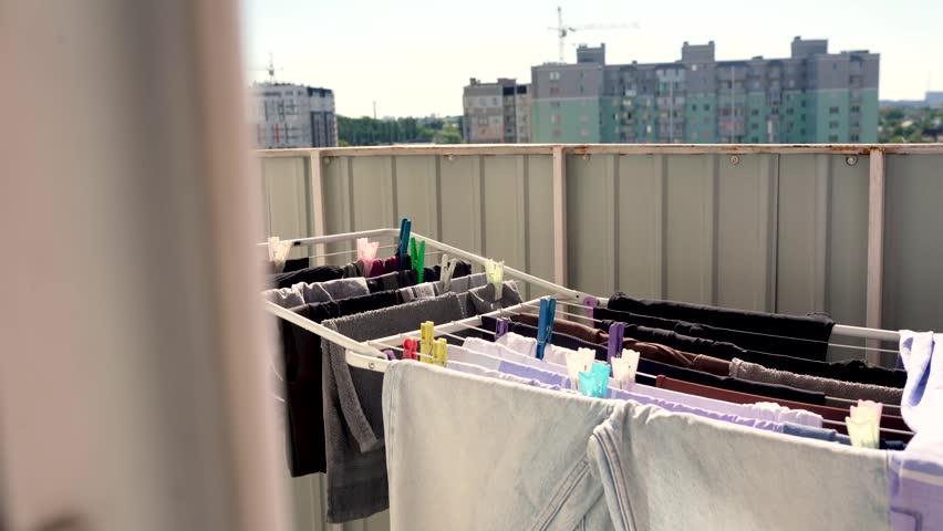 Clothes and linens are dried on a clothesline with clothespins on the balcony of the house, outside in the fresh air, in the sun