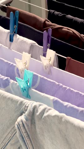 Clothes and linens are dried on a clothesline with clothespins on the balcony of the house, outside in the fresh air, in the sun