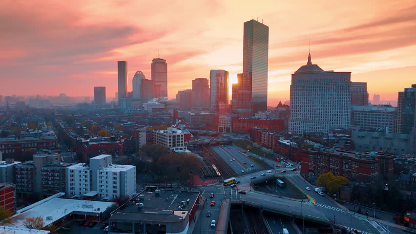 Skyline of modern Boston, Massachusetts, USA at the backdrop of pink sky. Aerial perspective on the highways and freeways with transport moving by.