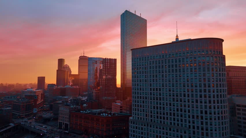 Modern skyscrapers of Boston, Massachusetts, USA in the light of setting sun. Flying above the lively city at sunset time.