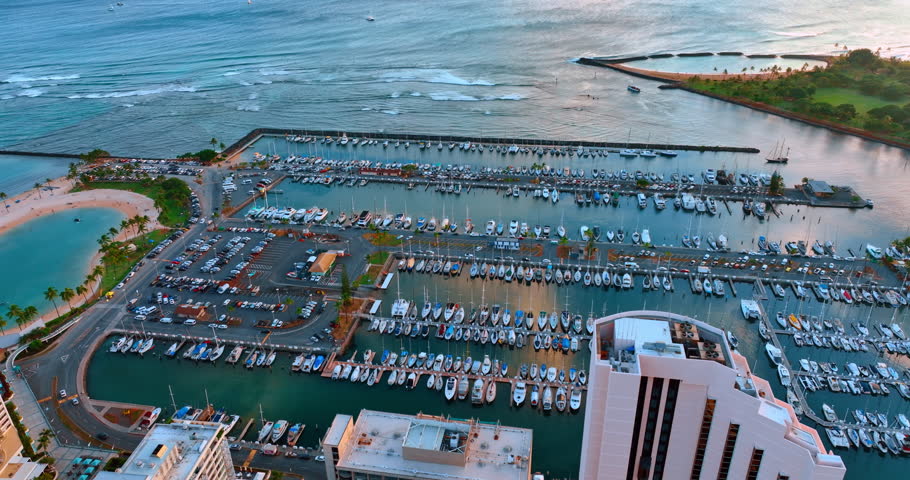 Amazing scenery of the yacht club with numerous boats at the berths. Drone footage over the coast of Honolulu, Hawaii, USA at sunset time.