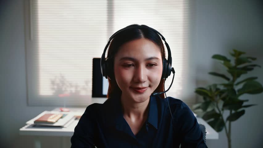 Professional asian woman operator working in a call center, wearing a headset and talking with a customer, providing technical support