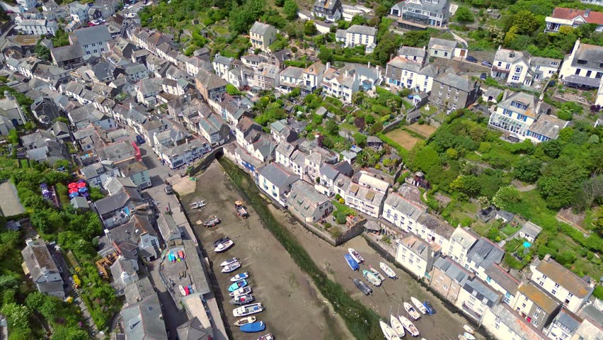 Aerial composite photographs showing the historic harbour and fishing boats nestled within the valley at Polperro village, revealing detailed views of the water and surrounding steep green hillsides. Polperro United Kingdom