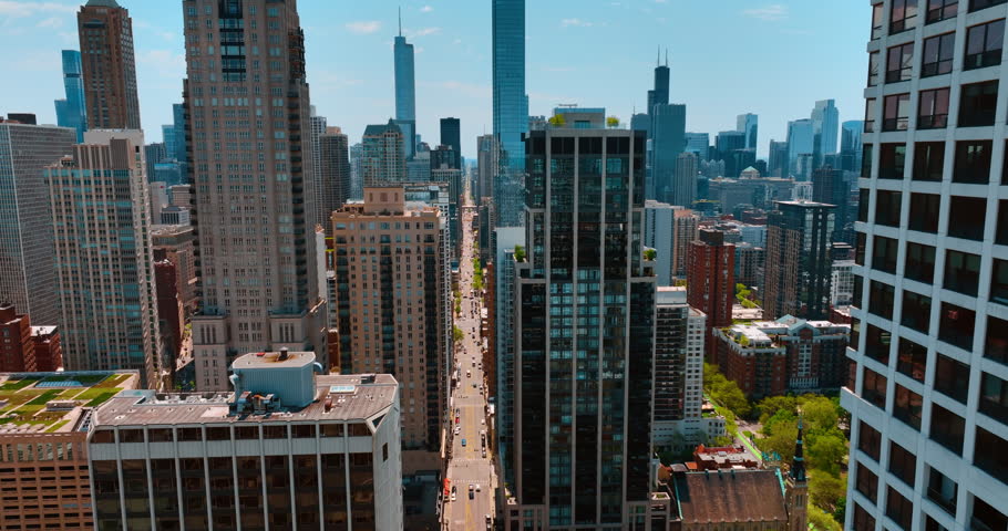 Footage over the long straight street passing among the high-rises and skyscrapers. Flight in the downtown of Chicago, Illinois, USA.