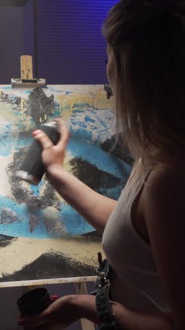 Young woman artist painting artwork with spray paint can in art studio. Creativity, talent, artistic expression, inspiration and contemporary art