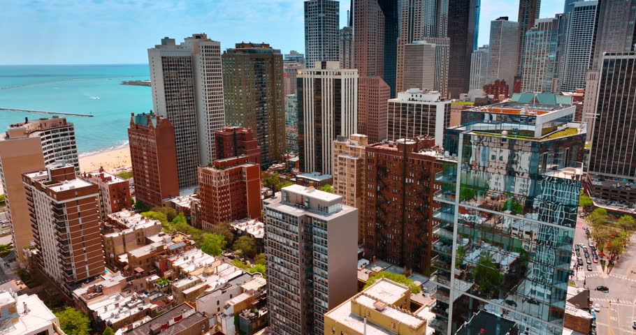 Bright residential area with green streets at the shore of lake Michigan. Flight over the cityscape of Chicago, Illinois, USA. Blue waterscape at backdrop.