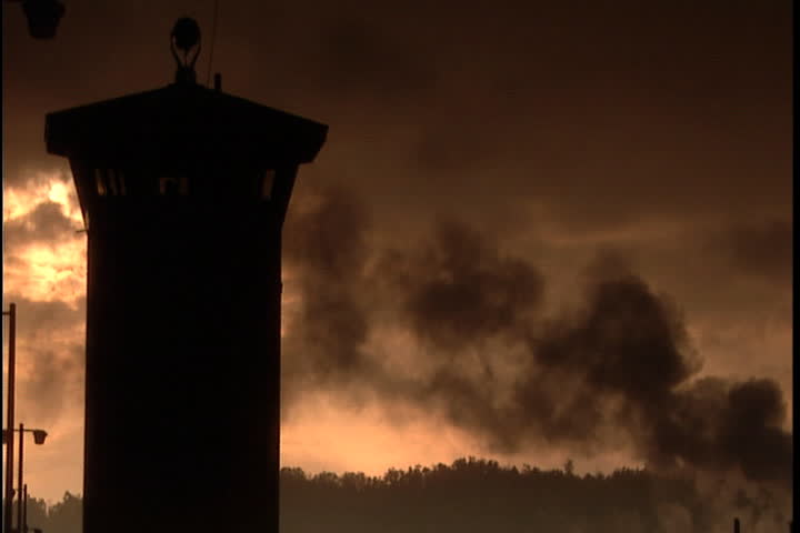 Silhouette of guard tower against orange sky with black smoke blowing from nearby building at Southern Ohio Correctional Facility in Lucasville, Ohio.