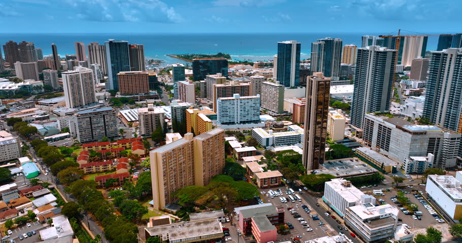 Approaching a beautiful green neighborhood with lovely blocks of flats. Stunning scenery of Honolulu, Hawaii, USA near the shore of the Pacific Ocean.