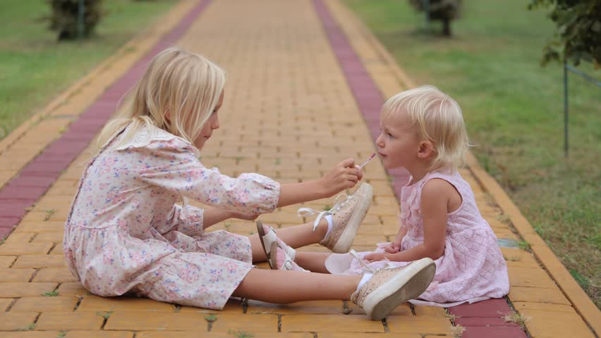 Older sister playing with younger toddler girl in a park