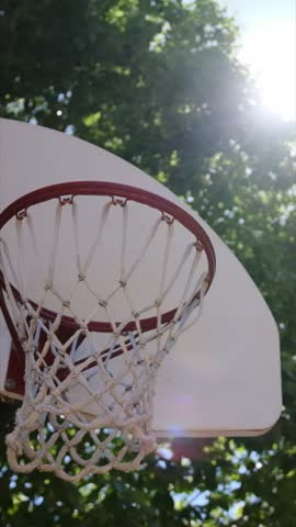 Basketball going through outdoor hoop in the sun
