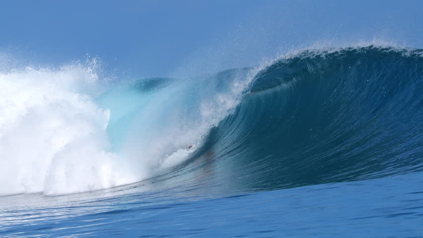 CLOSE UP, SLOW MOTION: Hollow section unloads with blowing spray and bright blue water as reef break comes alive. Warm tropics, heavy swell and perfect wave in surfing paradise of Mentawai Islands.