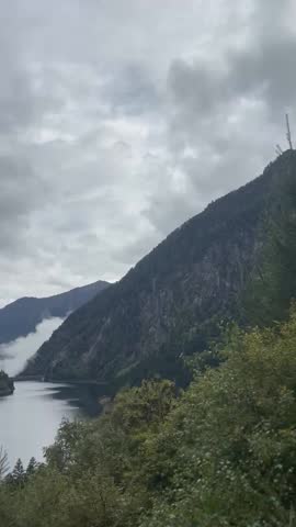 Clouds between mountains over a lake, aerial nature landscape