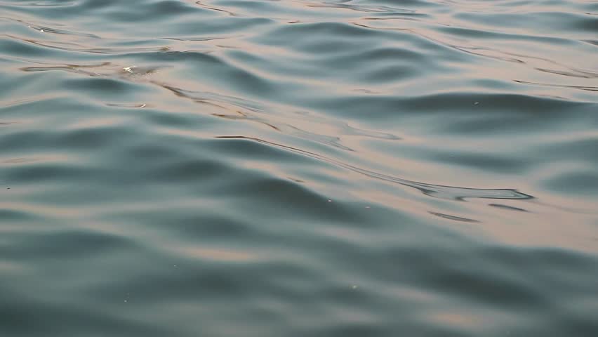 Close up of calm sea water surface with gentle ripples and soft waves. Blue green water background moving slowly during a peaceful day. Nature backdrop and liquid texture concept.